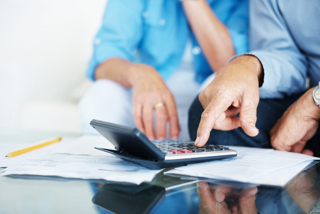 A couple's hands are pointing at a calculator