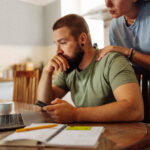 A man and woman at the dining table looking at a laptop concerned